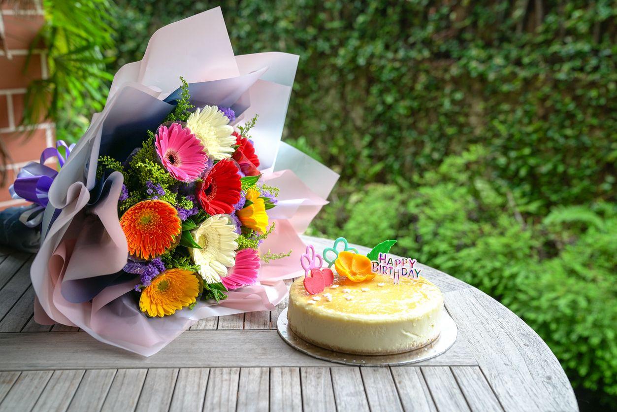 A bouquet of gerbera daisies with a birthday cake