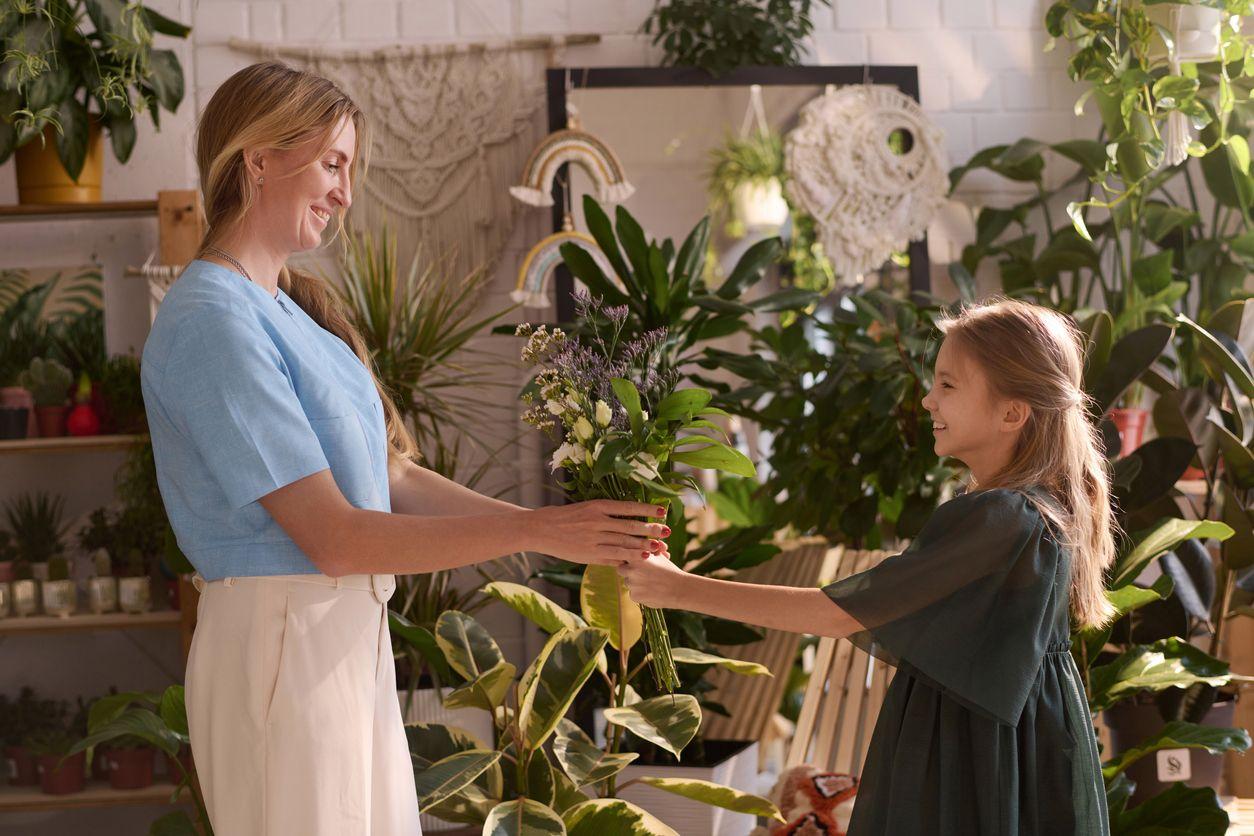 A girl gifts a flower bouquet to her mother