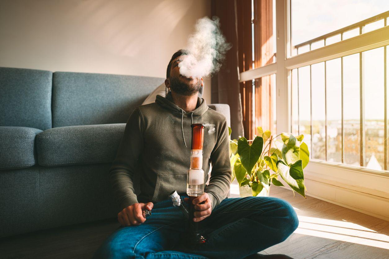 Man smoking bong at home
